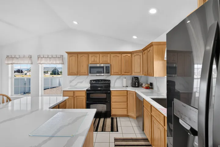 Kitchen featuring light wood cabinetry, white countertops, and a white tile backsplash