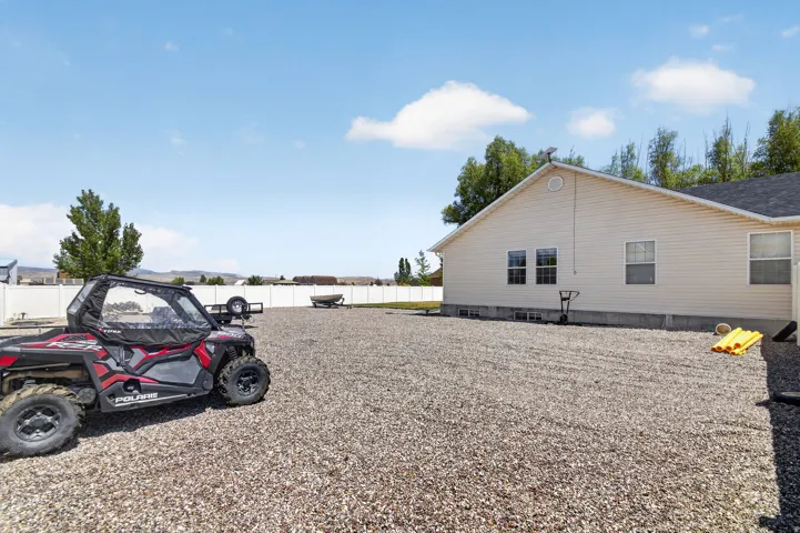 Expansive gravel yard featuring a durable vinyl fence and a neutral-toned siding exterior