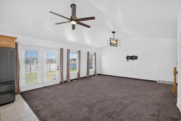 Spacious room featuring vaulted ceilings, plush carpet flooring, and multiple windows