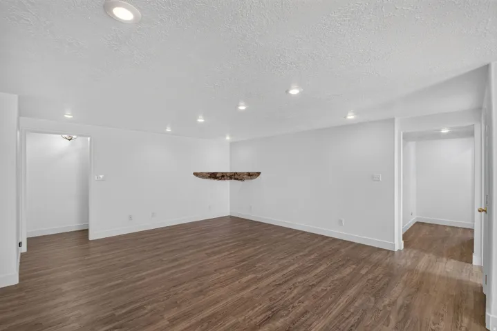 Spacious room featuring wood-finish flooring, white walls, and recessed lighting