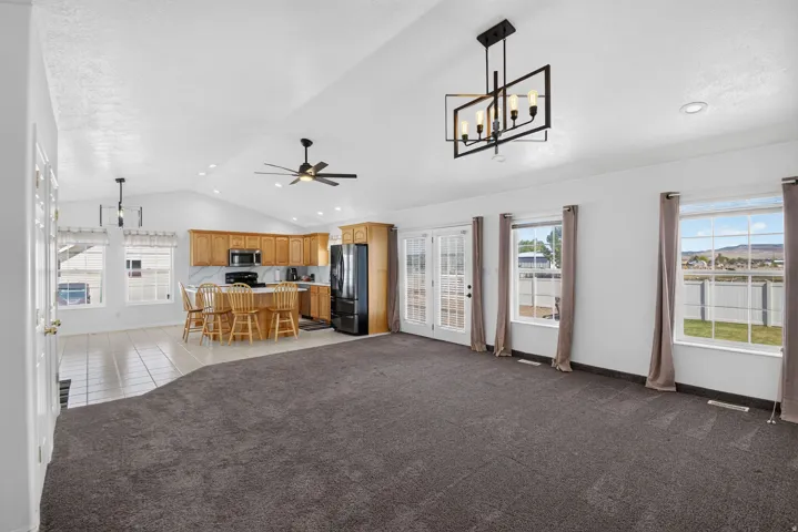 Open-concept living space featuring vaulted ceilings, a contemporary chandelier, and French doors