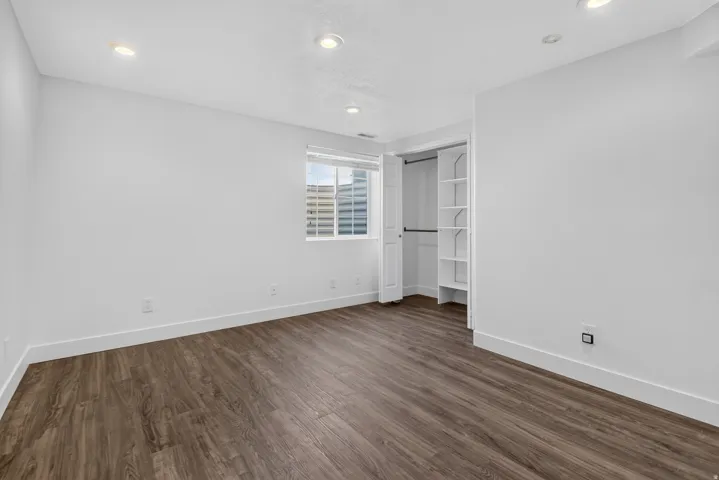 Spacious room featuring wood-finish flooring, white walls, and recessed lighting
