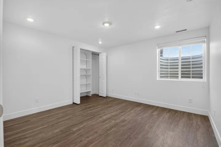 Spacious room featuring wood-finish flooring, white walls, and recessed lighting