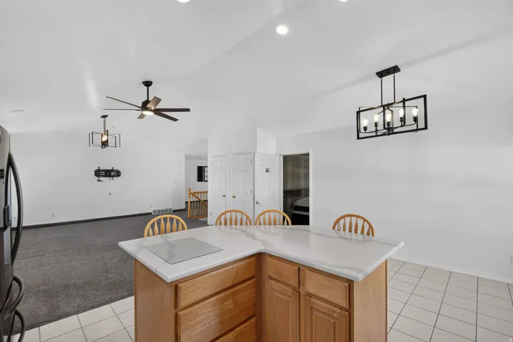 Kitchen island with light wood cabinetry, a white countertop, and tile flooring