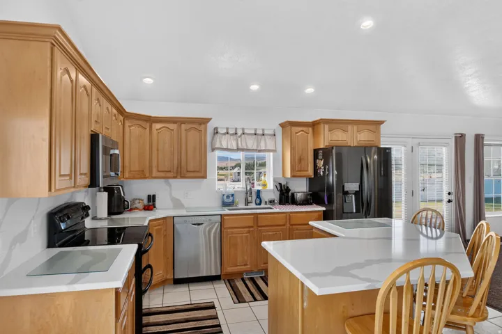 Kitchen featuring light wood cabinetry, white countertops with veining, stainless steel appliances, and recessed lighting