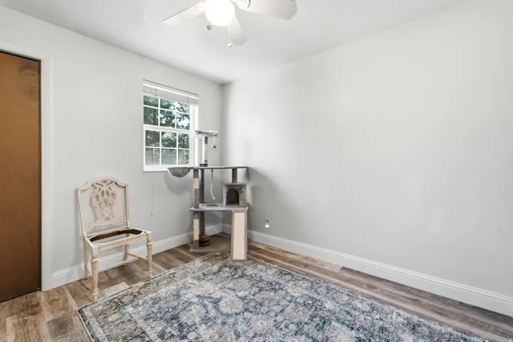 Interior room featuring a window with blinds, wood-finish flooring, and light-colored walls