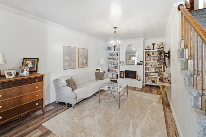 Living area featuring wood-finish flooring, a fireplace with a white brick surround, and built-in shelving