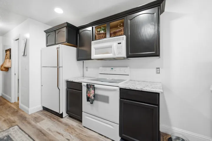 Kitchen featuring dark wood cabinetry, white appliances, a light-colored countertop, and a white subway tile backsplash