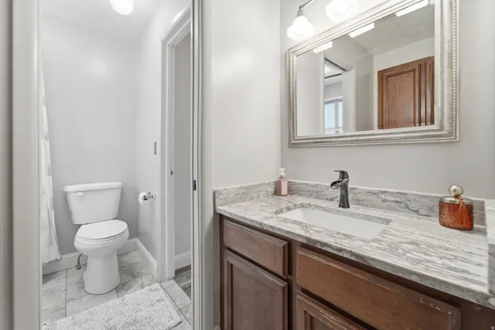 Bathroom vanity featuring a rectangular undermount sink, a dark bronze faucet, and a stone countertop