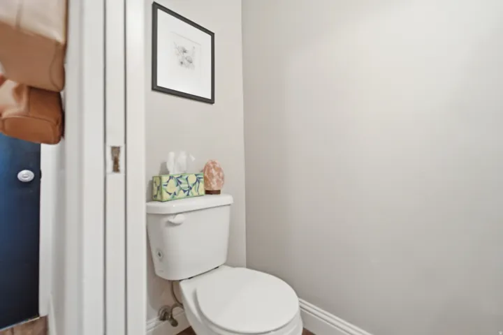 White commode with a framed art piece above, set against light-toned walls with white trim