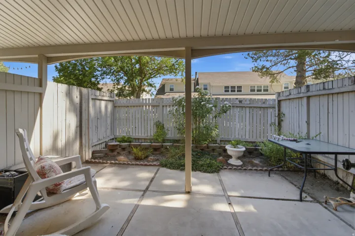 Covered concrete patio space featuring a slatted wood fence perimeter