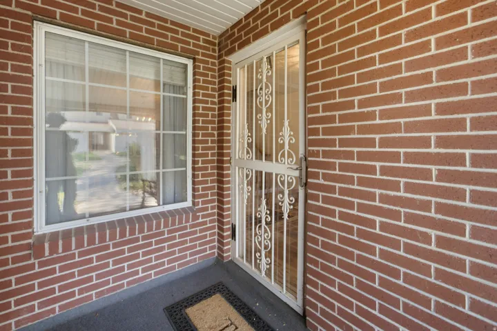 Brick facade with a white security door featuring scrollwork details