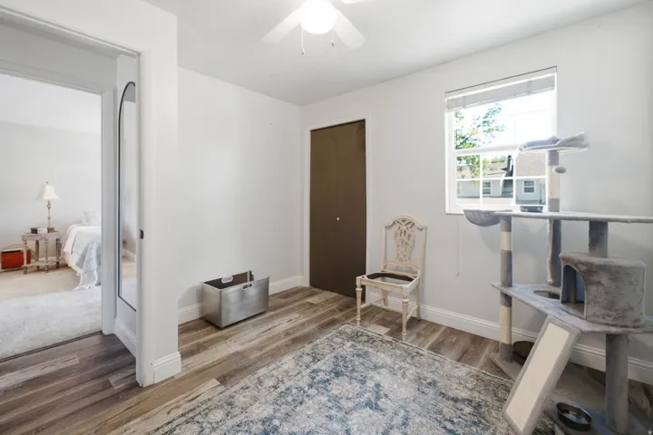 Interior room featuring wood-finish flooring, a neutral color palette, and a window with blinds