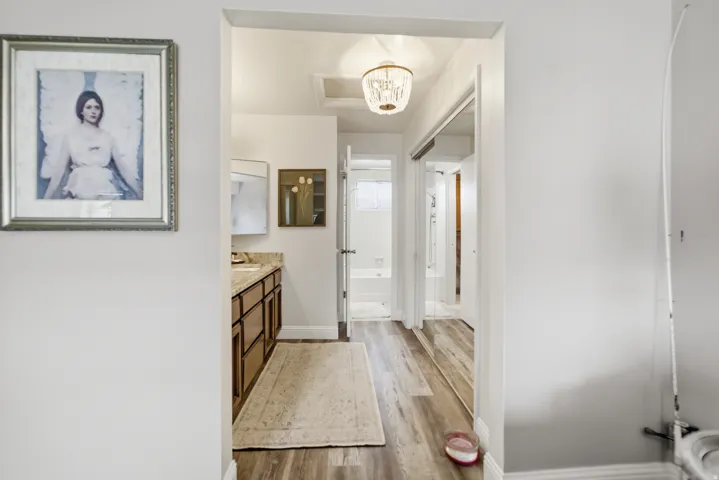 Hard-surface wood-finish flooring provides a durable surface throughout this hallway and bathroom area