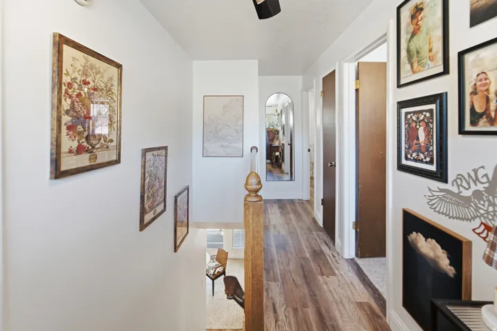 Hallway featuring wood-finish flooring, white walls, and dark wood doors