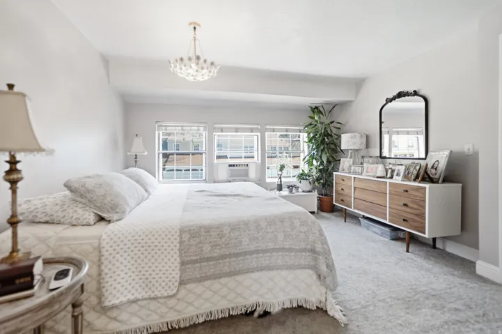 Spacious room featuring light gray carpeting, multiple windows for natural illumination, and a contemporary ceiling fixture