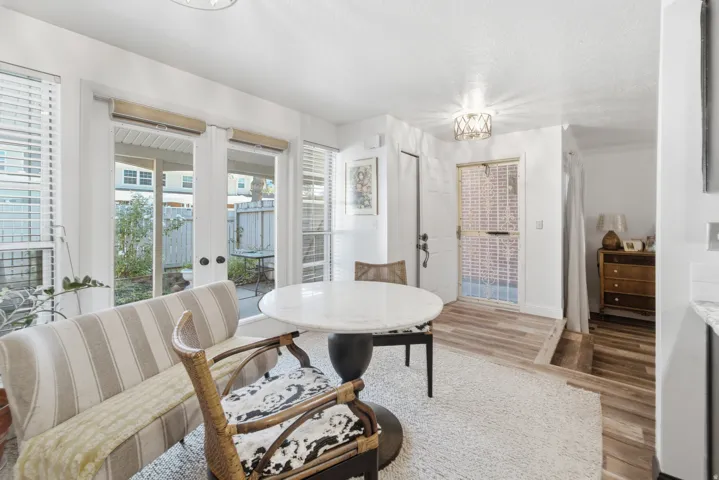 Dining area featuring a round stone-top table, wood-finish flooring, and multiple large windows with blinds