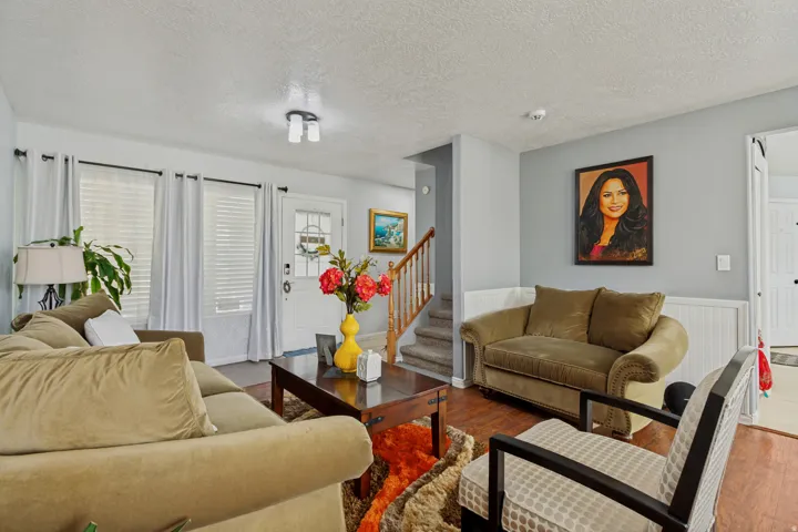 Bright, open living area featuring hardwood flooring, multiple seating zones with built-in upholstered furnishings, and abundant natural light from French doors and multi-pane windows