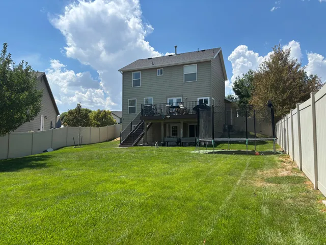 Expansive backyard featuring a manicured lawn, full privacy fencing, and mature trees