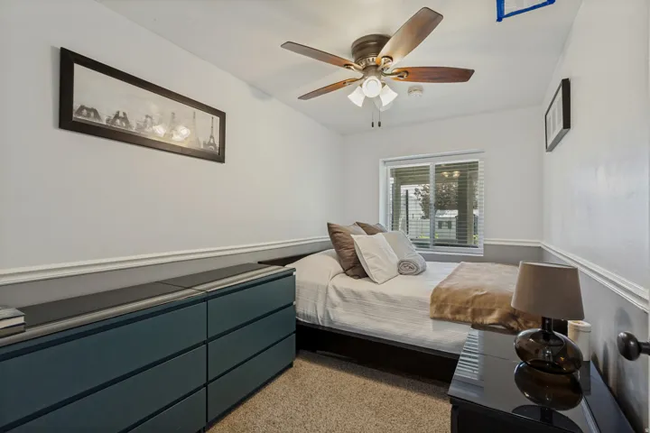 Carpeted room featuring a ceiling fan with light fixture, window with blinds, and white wall molding