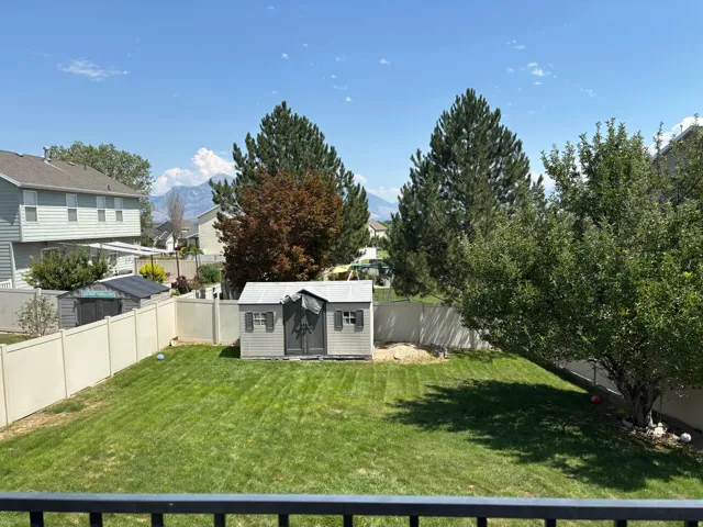 Expansive green lawn featuring a storage shed and mature trees