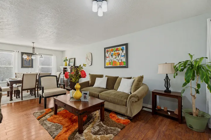 Open living area featuring hardwood flooring, a rolled-arm sofa with nailhead trim, wood-finish coffee table, and recessed ceiling lighting