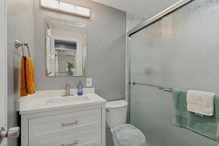 Elegant bathroom featuring a white vanity with ample storage drawers, white porcelain sink with chrome fixtures, and a framed mirror with integrated lighting