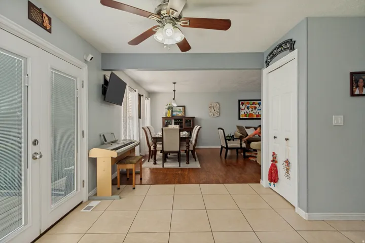 Light-toned tile flooring, white French doors, and a ceiling fan with integrated lighting