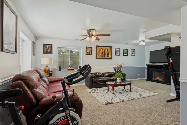 Recessed lighting, ceiling fan, carpeted flooring, wall-mounted television, and an electric fireplace