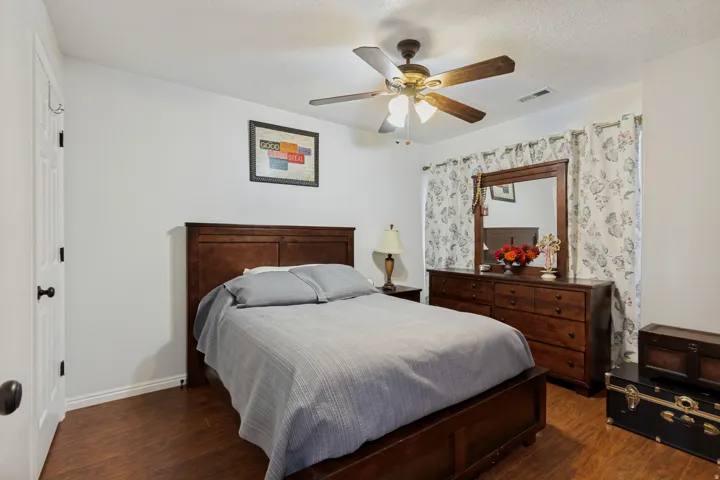 Wood-finish flooring, white painted walls, ceiling fan, and a paneled white door