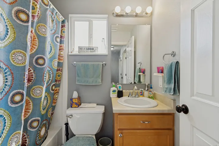 Bathroom featuring a single vanity with wood-finish cabinetry, a built-in sink, and a framed mirror