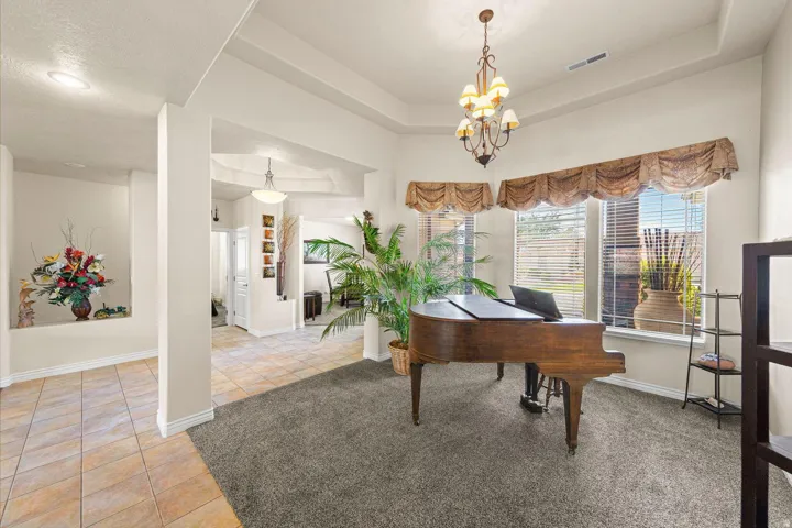 Carpeted room with a tray ceiling and a bronze chandelier