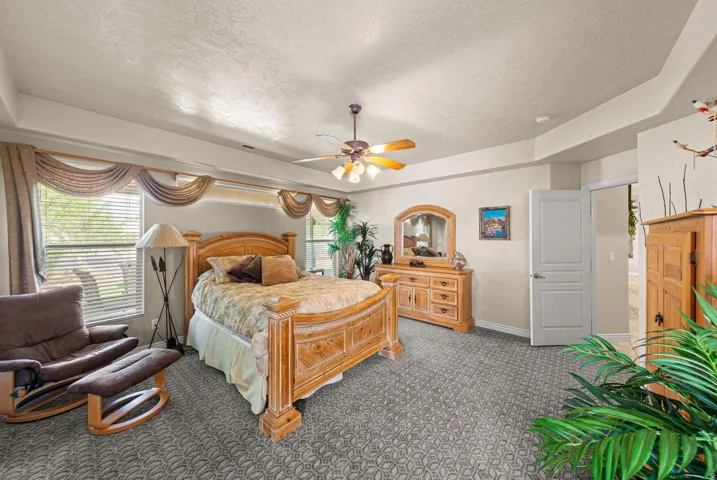 Spacious room featuring patterned carpet flooring, a tray ceiling, and a ceiling fan with integrated lighting