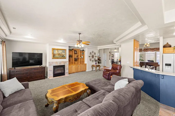 Spacious living area featuring a central fireplace with stone surround and hearth, integrated wood shelving, and a tray ceiling