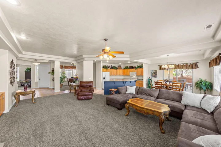 Spacious living area featuring tray ceilings with recessed lighting, carpet flooring, and an open-concept layout