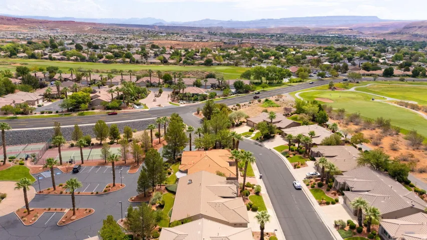 Expansive community showcasing mature landscaping, a paved street, and tennis courts