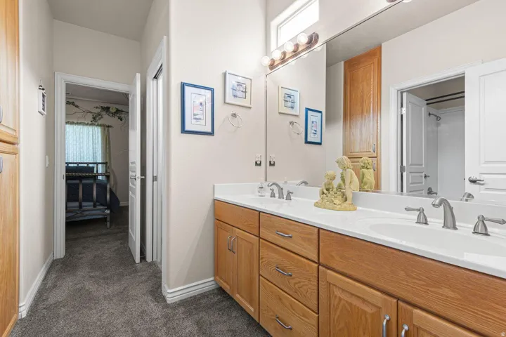 Double vanity featuring wood-finish cabinetry, white countertops, and brushed nickel fixtures