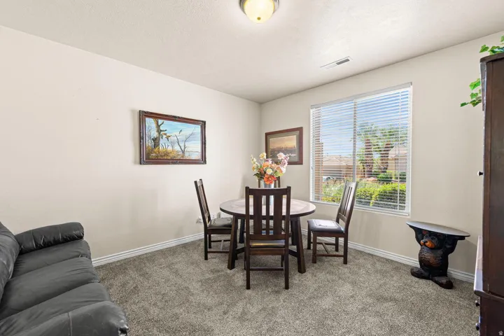 Open-concept room featuring neutral wall paint, gray carpet flooring, and a large window with white blinds
