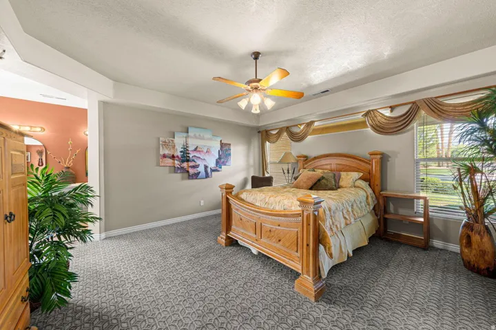 Spacious room featuring patterned carpeting and a tray ceiling with a ceiling fan