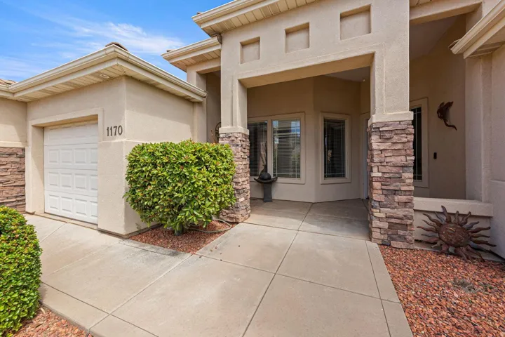 Stucco exterior with stone veneer accents, a covered entry, and an attached garage with a panel door