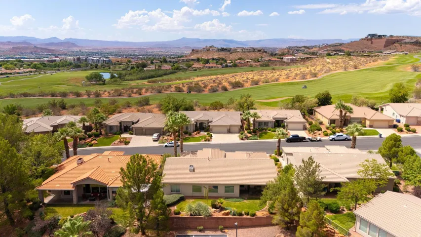 Residential property with tile roofing and mature landscaping, bordered by a golf course and distant mountains