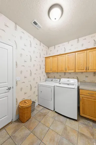 Utility room featuring upper cabinetry with wood-finish doors, a built-in counter, and tile flooring