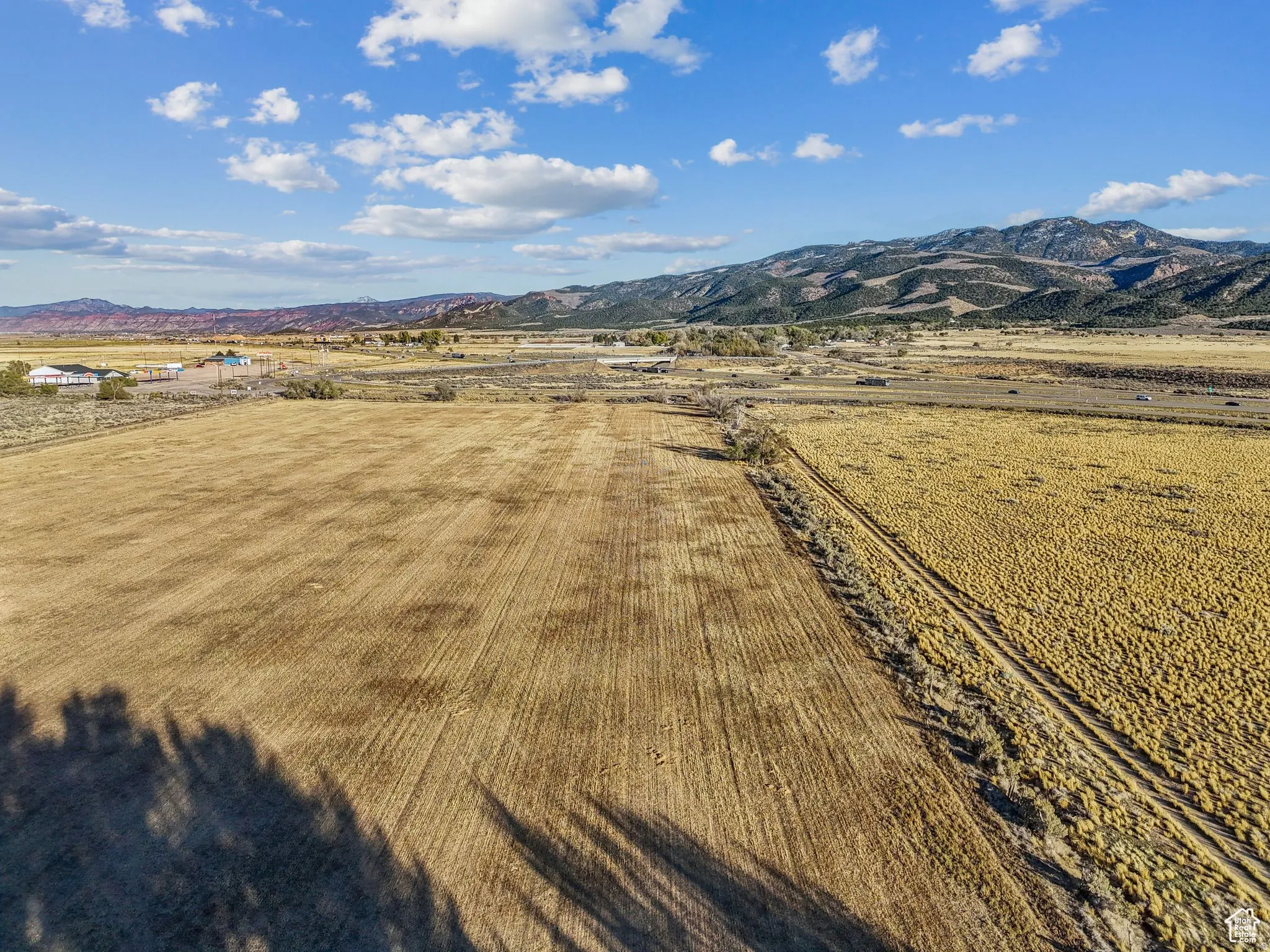 Expansive agricultural land featuring a tilled field and natural grasses