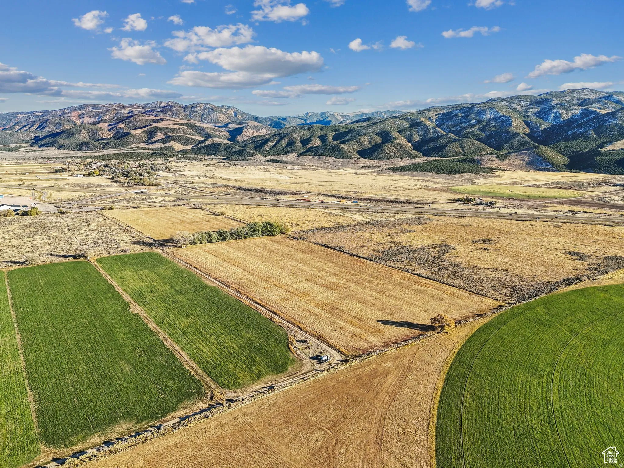 Expansive agricultural land featuring a mix of cultivated green fields and fallow brown fields