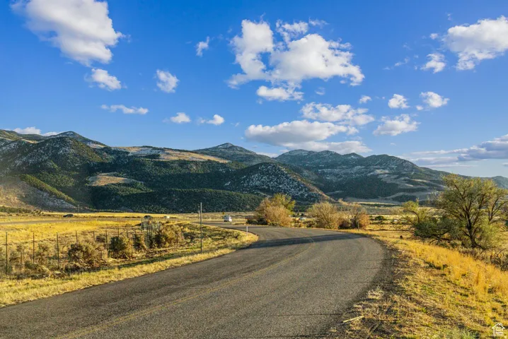 Paved road bordering expansive natural landscape with distant mountains