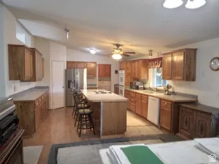 Spacious kitchen featuring wood-finish cabinetry, a central island with bar seating, and stainless steel appliances