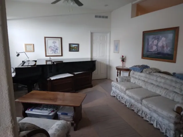 Vaulted ceiling, ceiling fan, white paneled door, wall niche, and light-toned walls