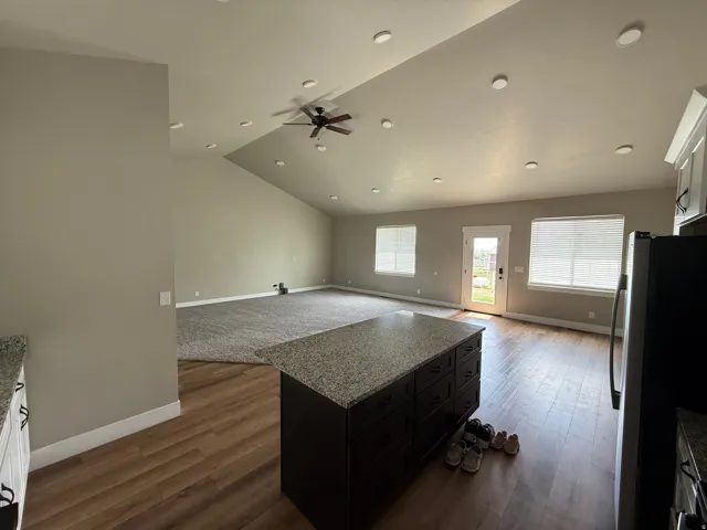 Open-concept living space featuring LVP wood-finish flooring, vaulted ceilings, recessed lighting, and a ceiling fan