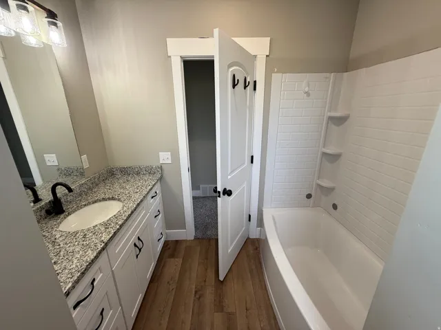 Bathroom featuring a white vanity with granite-style countertop, undermount sink, and matte black faucet