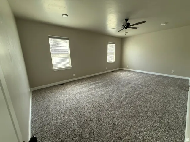 Spacious primary room featuring neutral carpeting, two windows with blinds, a ceiling fan, and recessed lighting